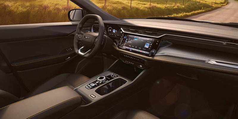 Interior view of SUV showing its dashboard, touchscreen, steering wheel, and center console.