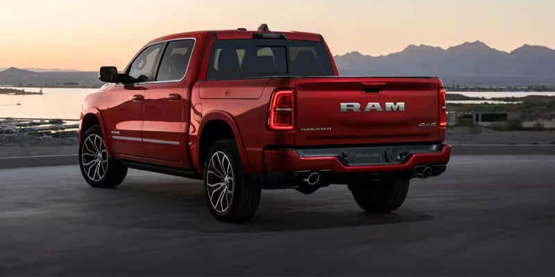 A red Ram pickup truck parked at sunset with mountains in the distance.